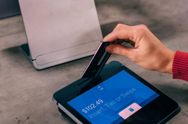 Person swiping their credit card on a POS machine