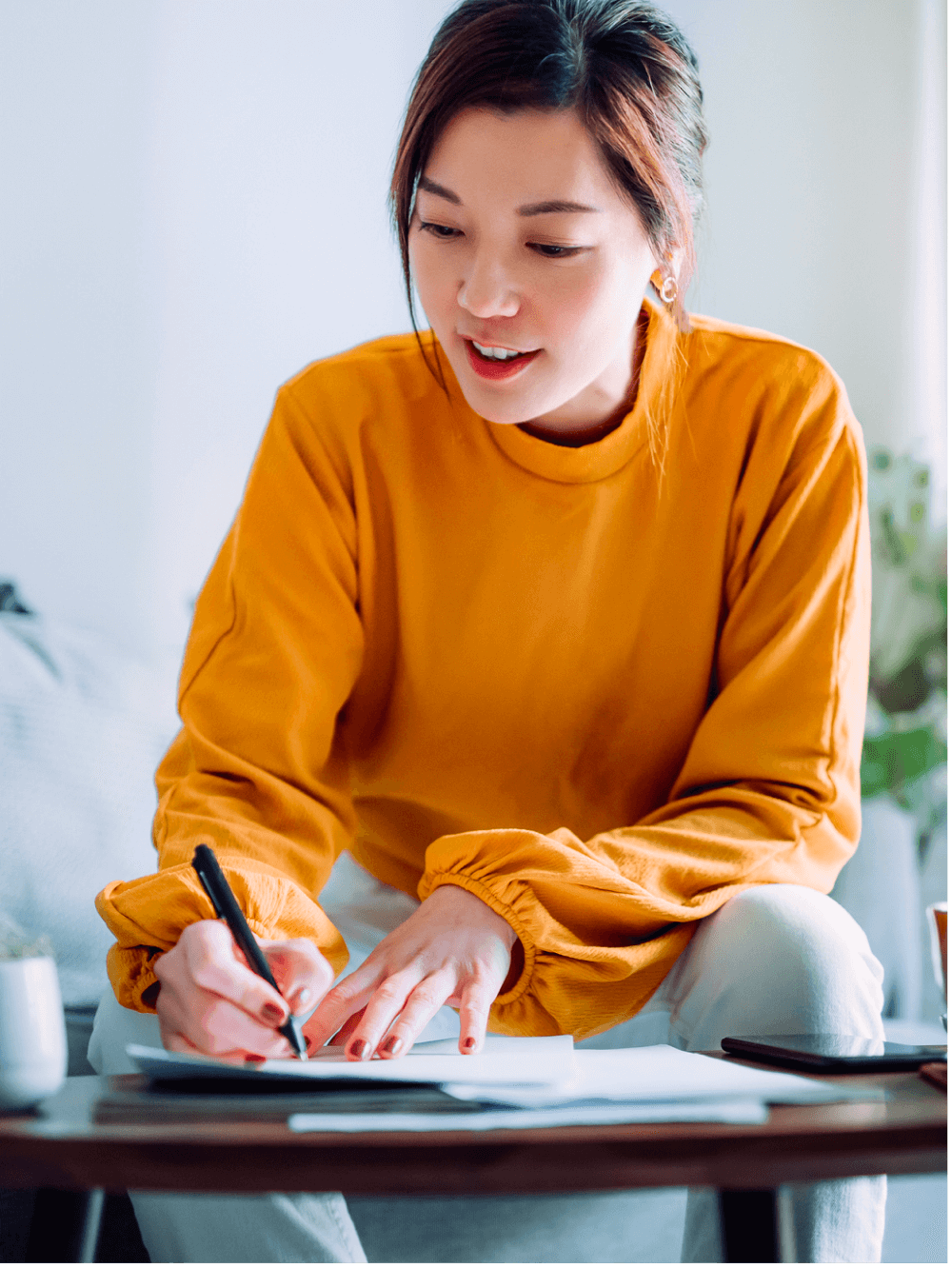 Woman on couch writing on a paper